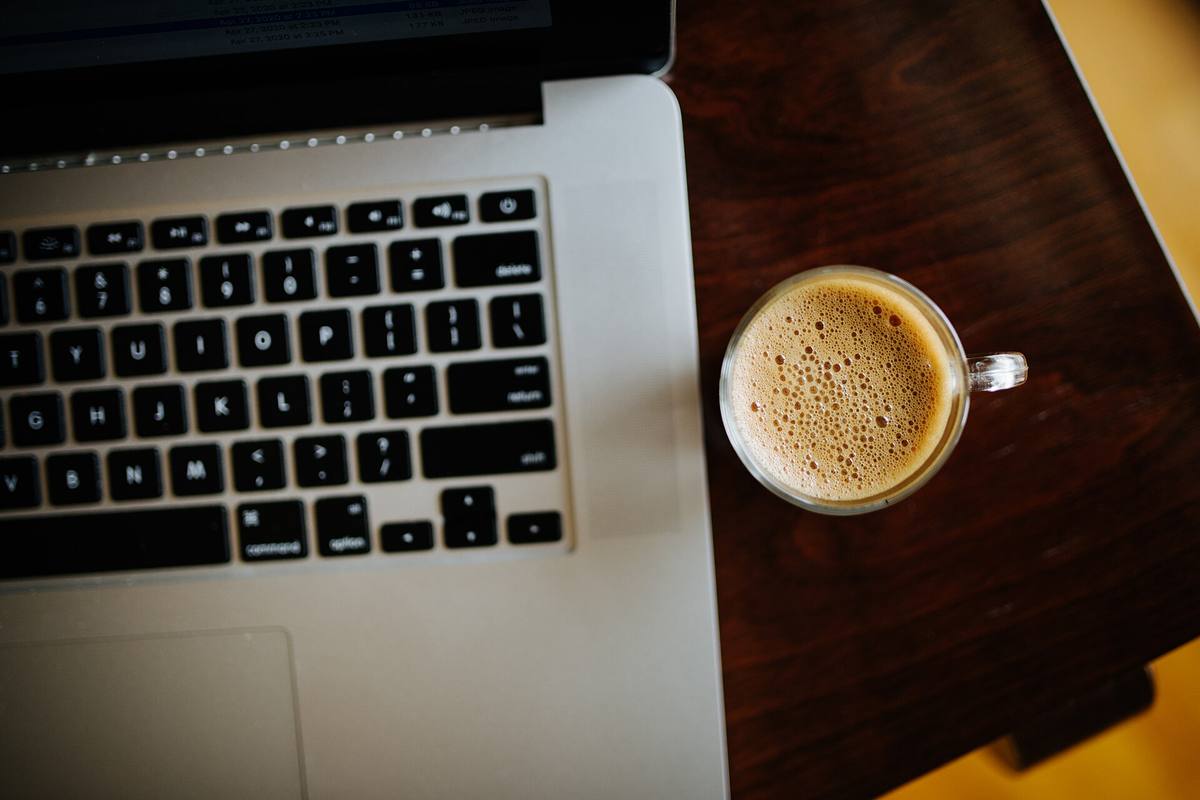 Meja kerja hangat dengan laptop dan secangkir kopi untuk membaca informasi dengan tenang