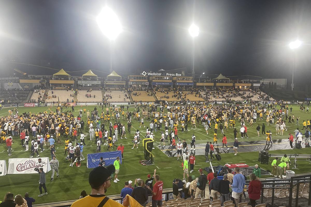 Stadion sepak bola di malam hari dengan lampu sorot menyala terang